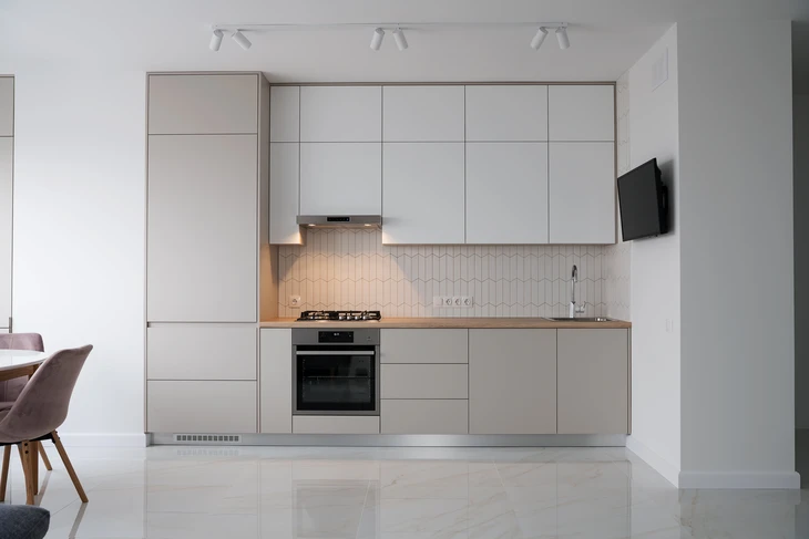 Cuisine moderne équipée en bois clair avec éclairage LED sous meubles hauts
