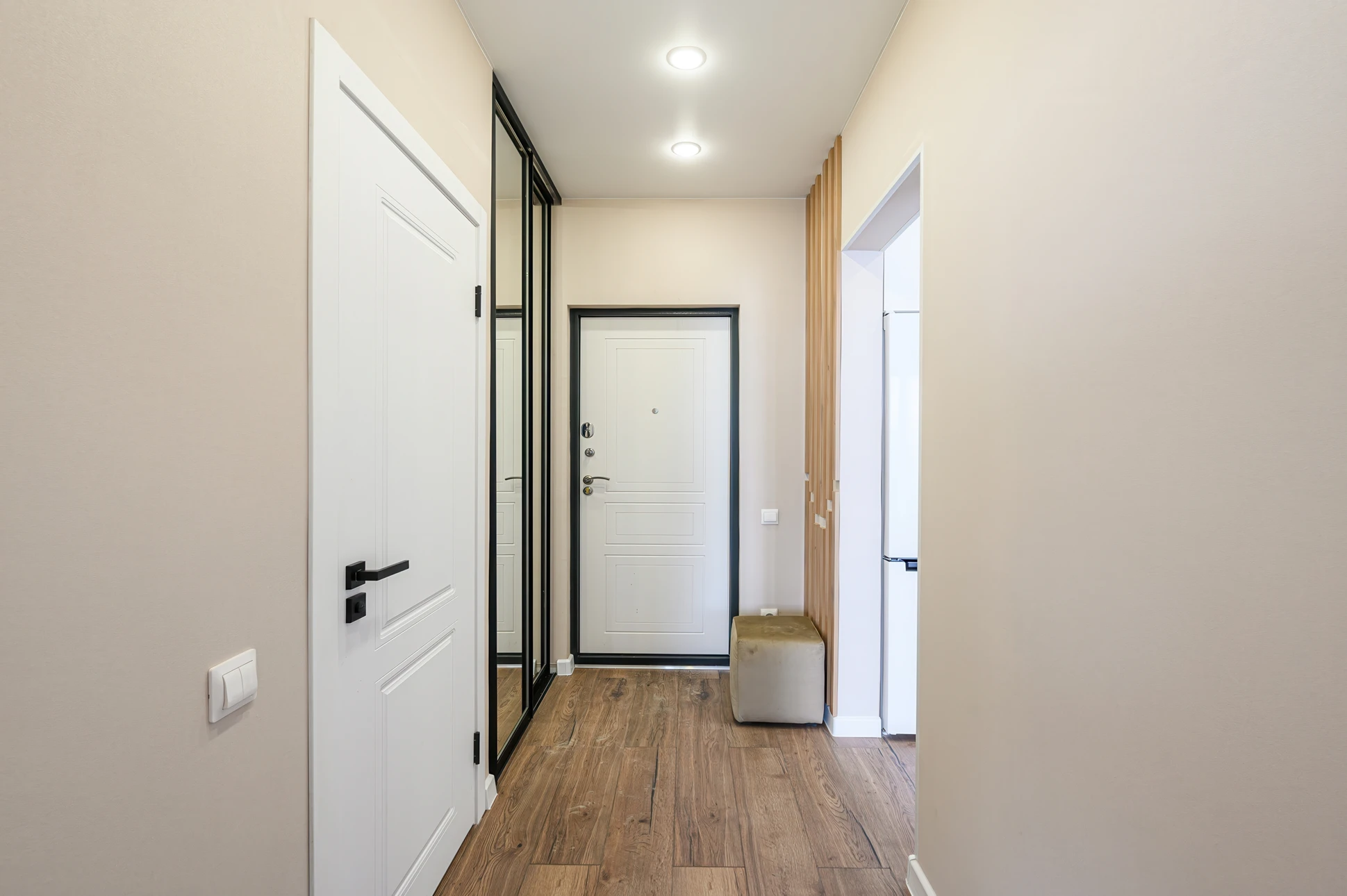 Intérieur d'habitation moderne avec porte coulissante en bois clair ouverte révélant une salle de bain
